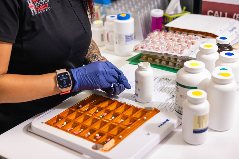 Gloved pharmacy technician filling a compounding tray